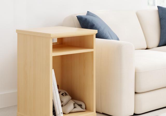 Compacte houten bijzettafel naast een bank in een lichte studio