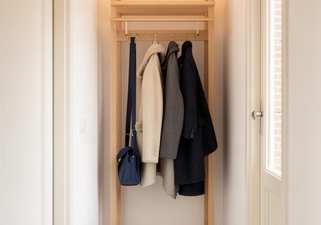 Compacte houten kapstok met jassen in een smalle hal