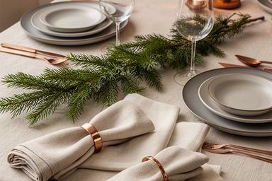 Feestelijke set tafeltextiel met servetringen en dennentak op een gedekte tafel