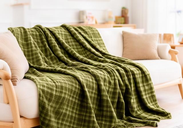 Stevige olijfgroene plaid over een lichte bank in een gezinswoonkamer